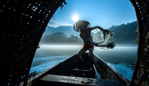 Second Place Winner-- &quot;Fishing with a Net” by Liming Cao of China; Fishermen fish with nets early in the morning. They sell fish at the market to make a living.